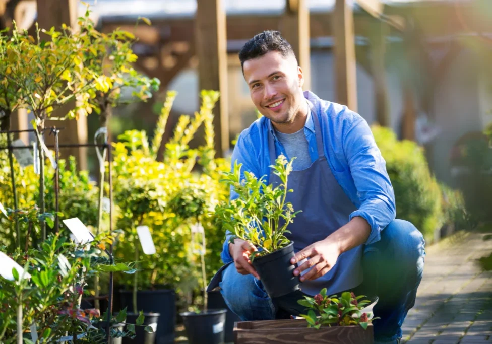 Man gardening with potted plants, smiling outdoors.